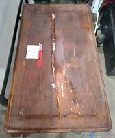 Full view of rectangular wooden table showing crack and wear