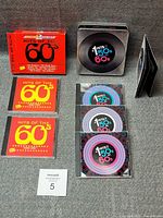 Entire lot showing both CD sets: red slipcase set, metal tin set, jewel cases, booklet