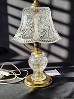 Full view of cut crystal table lamp, brass-tone foot and cord visible