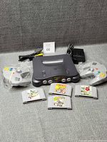 Full lot: console, two controllers in plastic, power adapter, A/V cable, four game cartridges