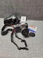 Full lot view: camera with lens, case, lens cap, strap