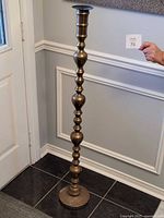 Full view of brass floor standing candle holder against wall, shows overall form