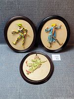 Front view of three oval framed clown plaques