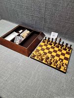Chess/checkers set showing storage box interior compartments with bagged pieces and board beside