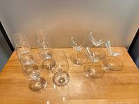 Group of nine clear stemmed glasses—five wine, four martini—on wooden surface