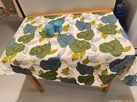 Tablecloth draped on table showing full leaf pattern, candles placed on top