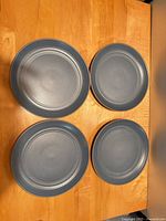 Four matte blue-gray stoneware plates front view