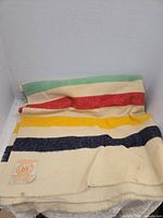Full blanket folded showing stripe pattern, cream base and attached label