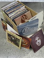 Box of LP records with sleeves visible and several albums displayed in front