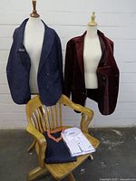 All four garments displayed: two blazers on mannequins, sweater and packaged shirt on chair
