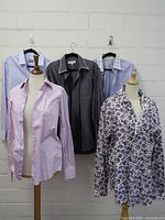 Five dress shirts displayed on mannequins and hangers