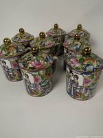 Front view of eight porcelain mugs with lids