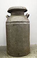 Front view of galvanized milk can showing embossed branding and lid