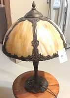 Side view of lit slag glass lamp showing shade color and base detail