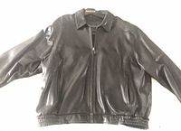 Front view of black leather bomber jacket showing collar, zipper, pockets and waistband