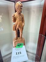 Front view of carved wood figure displaying overall form and height note