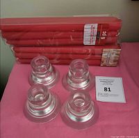 Pack of red candles and four glass votive holders on table