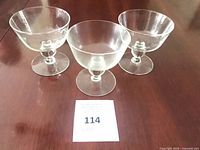 Front view of three clear glass sherbet glasses showing bowl shape and ball stems