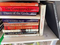 Stack of eleven hardcover travel and history books on shelf