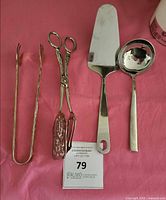 All four stainless steel serving utensils laid out on pink cloth