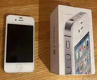 Front view of white iPhone 4S next to its box