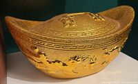 Gold ceramic ingot coin bank side view showing dragon motif