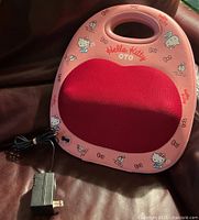 Front view of pink OTO Hello Kitty back massager with power adapter