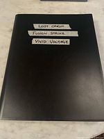 Closed black binder labeled with tape strips listing included expansions