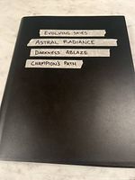 Black binder closed with tape labels listing included sets