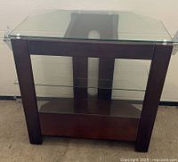 Front view of dark wood TV stand with glass top and shelves