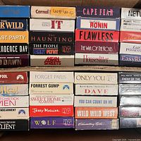 Box top view showing multiple VHS spines such as Half Baked, Cape Fear, Forrest Gump