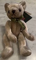 Front view of cream Harrods teddy bear with ribbon and hang tag