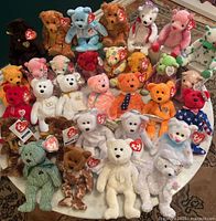 Full group shot of 31 Ty Beanie Baby bears arranged on round table, all tags visible