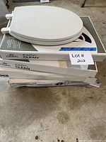 Stack of five toilet seats, top seat loose, three Church boxes visible, partial view of bottom boxes