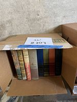 Box containing eight hardcover books, spines showing