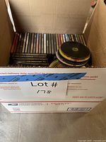 Box of numerous CD jewel cases stacked, loose discs on top
