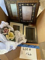 Box containing ornate frames and porcelain floral figurine