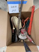 Top view of box with angle grinder, drill bits, sanding discs and assorted tools