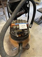 Full view of Ridgid wet/dry vacuum showing drum, handle, hose, and casters