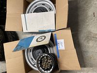 Two boxed steel wheels with hub cap and lug nuts visible