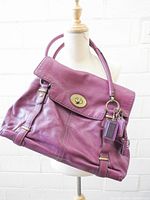 Front view of Coach fuchsia pebbled leather shoulder bag showing turnlock flap and hangtag