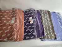 Five unopened packs of tissue paper in various colours