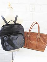 Black leather shoulder bag and cognac tote shown together for scale and comparison
