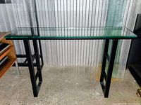 Console table angled view showing glass top and metal frame