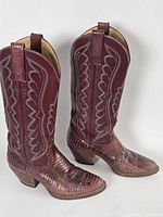 Full view of both burgundy embossed leather cowboy boots showing texture and stitching