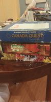 Stacked view showing three board game boxes: Canada Quest, The All Canadian Trivia, Ottawa Monopoly variant