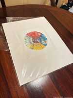Full view of matted Alex Janvier Morning Star print in plastic sleeve on table