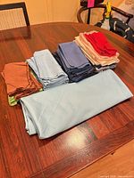 Stacked light blue tablecloth and multiple bundles of colored napkins