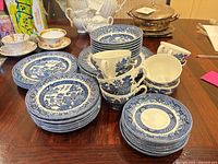 Full grouping of Blue Willow dinnerware showing stacks of plates, bowls and teacups