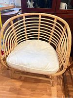 Front view of IKEA Buskbo rattan armchair with beige cushion